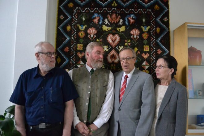 Jouko Lehtisalo (vas.), Jarmo Puntalo, yhteiskoulun entinen rehtori Kari Koivuranta ja vaimonsa Marketta poseeraavat koulun käytävän seinän Mouhijärven ryijyn edessä.